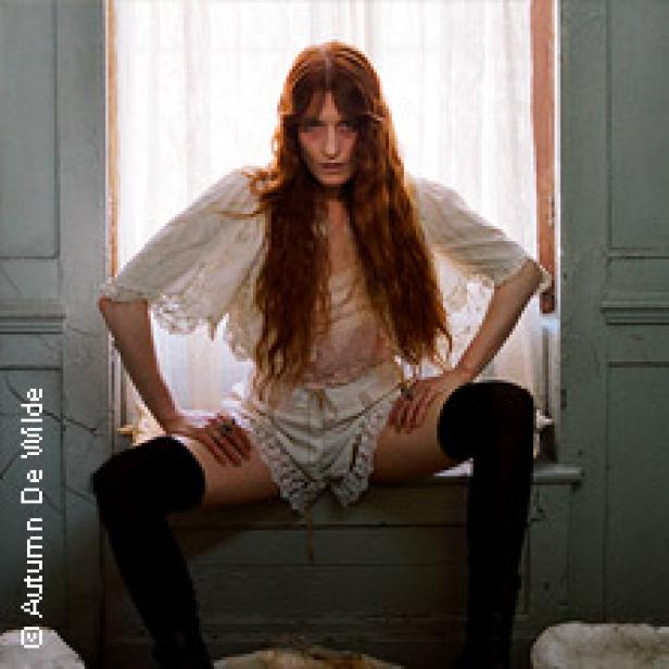Florence Welch sitzt in Unterwäsche und Overknees auf einem Fensterbrett.