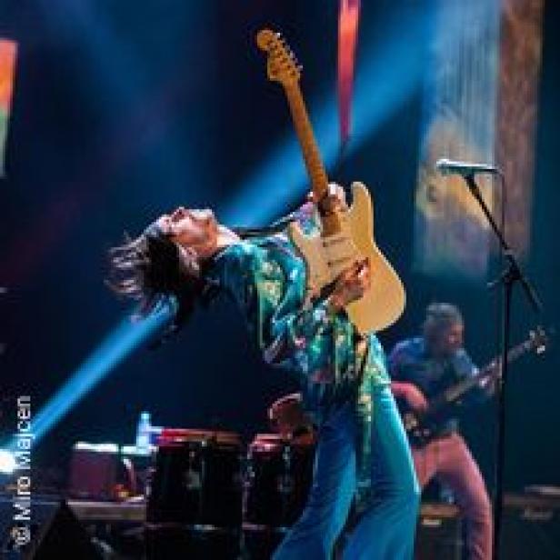 Ein Gitarrist spielt auf der Bühne mit zurückgelehntem Kopf.