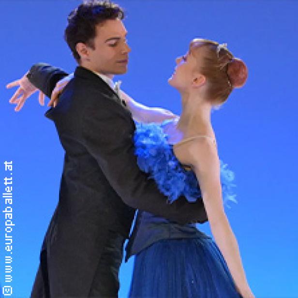 Ein Tänzerpaar in Kostümen tanzt vor einem blauen Hintergrund.