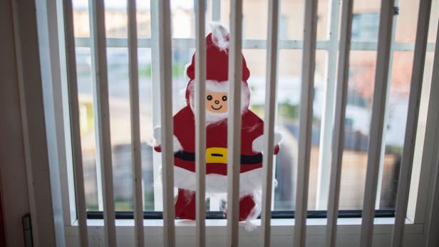 Ein weihnachtlicher, selbstgebastelter Weihnachtsmann hängt am Fenster.