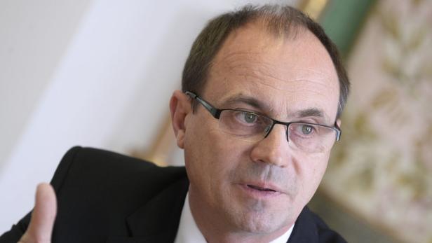 Ein Mann mit Brille und dunklem Anzug blickt in die Kamera.