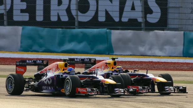 Zwei Formel-1-Autos von Red Bull rasen auf einer Rennstrecke nebeneinander her.