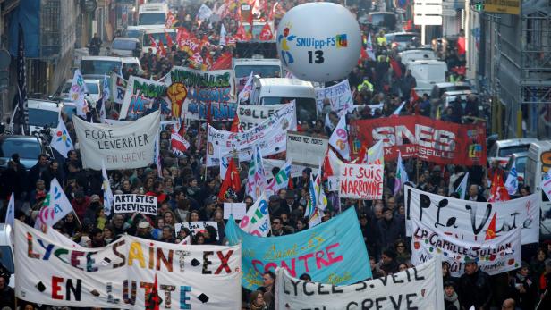 Eine Demonstration mit vielen Menschen, Bannern und Flaggen in einer Stadt.