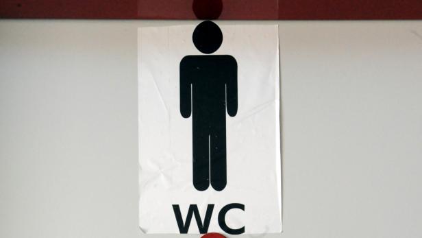 Ein Schild mit der Aufschrift „WC“ und einem Piktogramm einer männlichen Person.