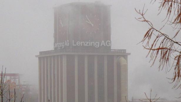 Ein hoher Turm mit der Aufschrift „Lenzing AG“ ist im Nebel zu sehen.