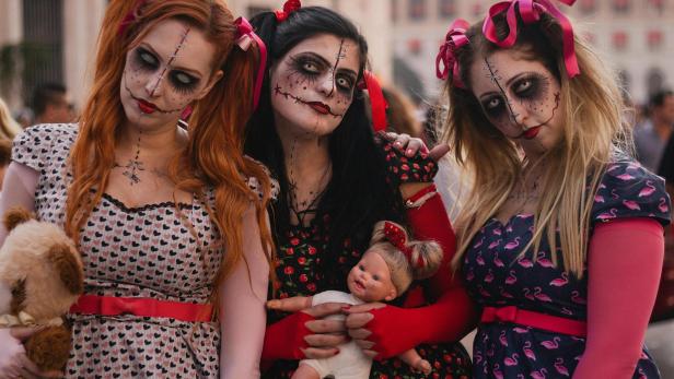 Drei Frauen mit Halloween-Makeup und einer Puppe.