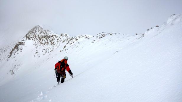 Ein Bergsteiger erklimmt einen schneebedeckten Berg.