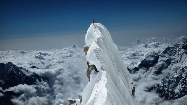 Ein Bergsteiger auf einer Bergspitze.