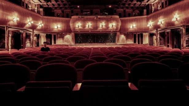 Ein Mann sitzt alleine in einem Theater.