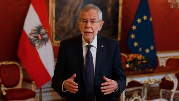 Alexander Van der Bellen spricht vor der österreichischen und der EU-Flagge.