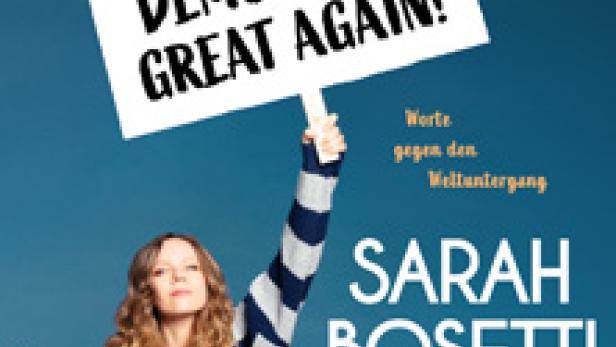 Sarah Bosetti hält ein Schild mit der Aufschrift „Make Democracy Great Again!“ hoch.