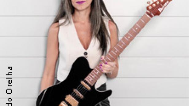 Eine Frau mit langen Haaren hält eine schwarze E-Gitarre in der Hand.