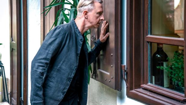 Mann blickt von außen durch ein Fenster