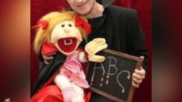 Ein Mann mit einer Puppe und einer kleinen Tafel, auf der ABC steht.