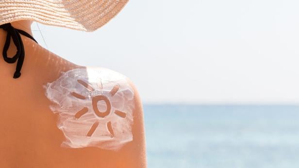 Sunscreen lotion in sun shape on tanned woman's shoulder