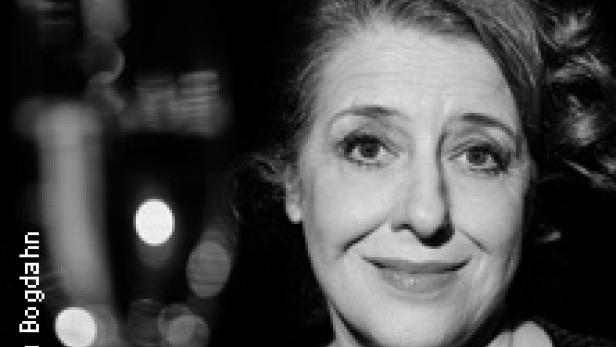 Schwarzweiß-Porträt einer lächelnden Frau mit lockigem Haar.