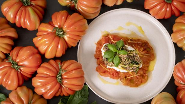Ein Teller mit frischen Tomaten, darauf eine Scheibe Käse.