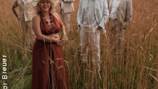 Eine Musikgruppe steht in einem Feld mit hohem, goldenem Gras.