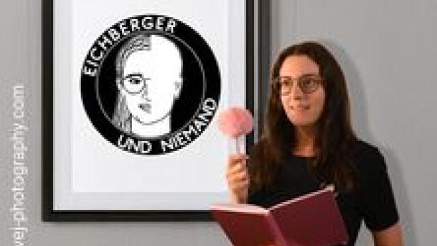 Eine Frau steht vor einem Bild mit der Aufschrift „Gemeindebau“ und dem Porträt einer Person.