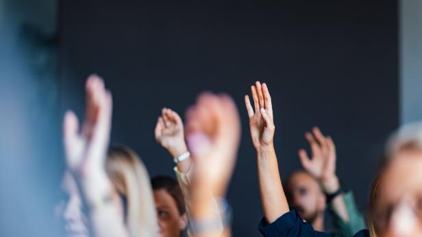 Engaged Audience Raising Hands at Business Event