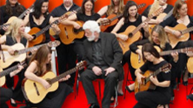 Eine Gruppe von Gitarristen spielt gemeinsam auf der Bühne bei einem Jubiläumskonzert.