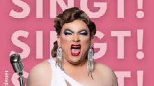 Eine Dragqueen mit Mikrofon singt vor einem pinkfarbenen Hintergrund mit dem Wort „Singt!“.