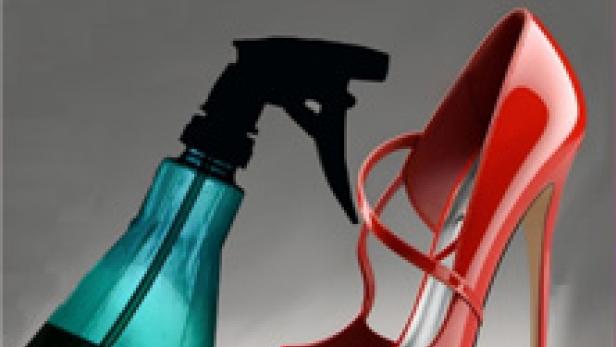 Ein roter High Heel steht neben einer blauen Sprühflasche.