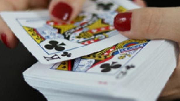 Eine Person mischt einen Stapel Spielkarten.