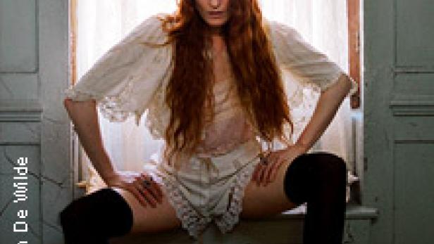 Florence Welch sitzt in Unterwäsche und Overknees auf einem Fensterbrett.
