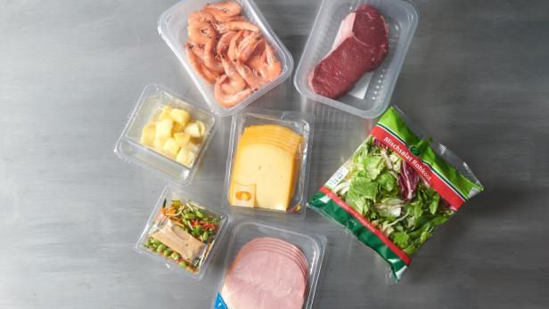 Eine Auswahl an Fleisch, Käse und Gemüse in Plastikbehältern, appetitlich angerichtet.
