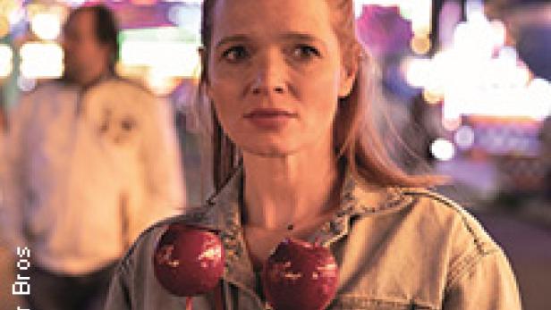 Eine Frau hält zwei rote Zuckeräpfel auf einem Jahrmarkt.