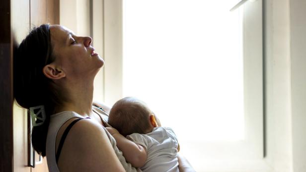 Tired concerned mother rocking sleeping baby.