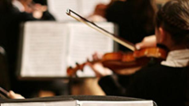Ein Orchester spielt Musik, Notenblätter im Vordergrund.