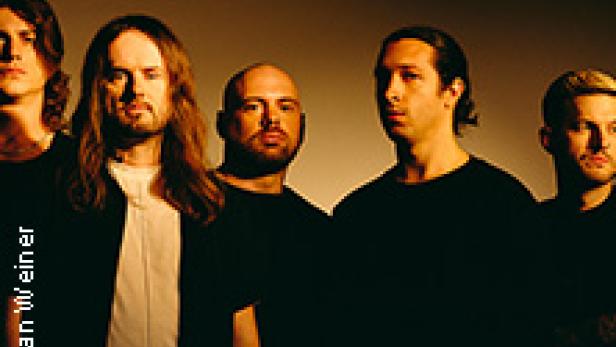 Fünf Männer stehen vor einem dunklen Hintergrund.