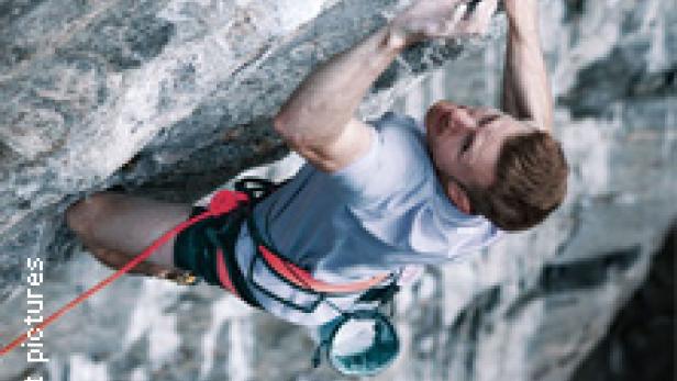 Ein Mann klettert an einer steilen Felswand.