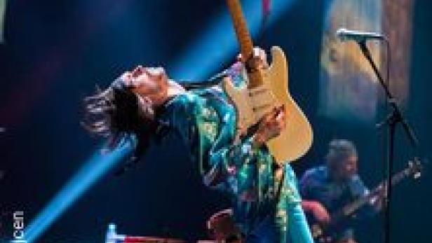 Ein Gitarrist spielt auf der Bühne mit zurückgelehntem Kopf.