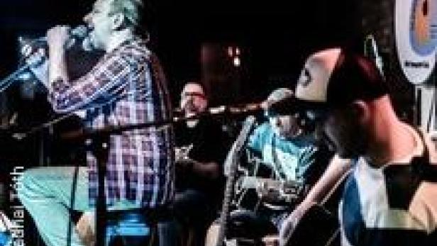 Eine Band tritt live auf der Bühne auf, der Sänger singt ins Mikrofon.