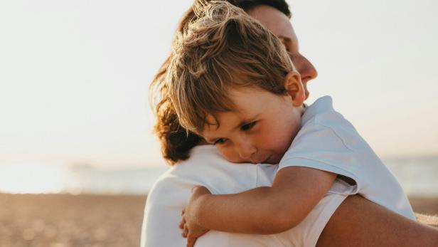 Mutter umarmt ihren Sohn am Strand.