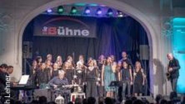 Ein Chor tritt auf einer Bühne vor Publikum auf.