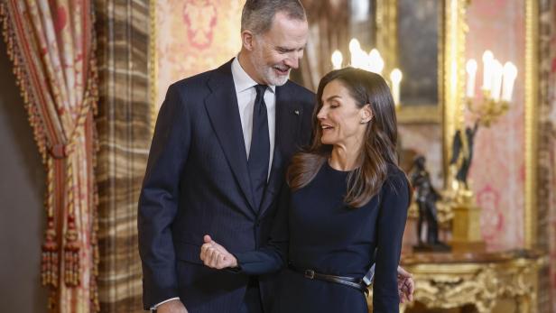 König Felipe und Königin Letizia stehen in einem eleganten Raum und schauen einander an.