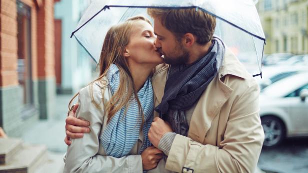 Küssendes Paar unter einem Regenschirm