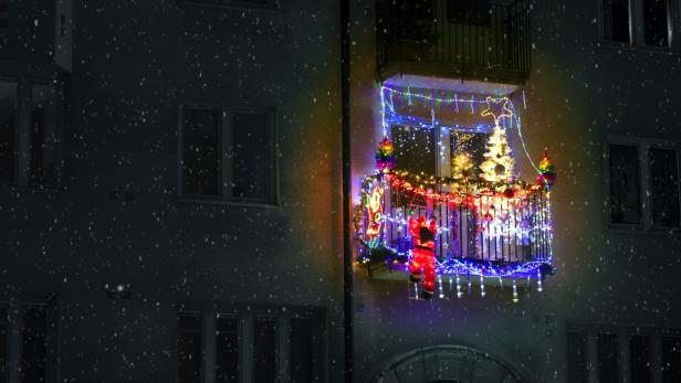 red jingle bells, lights, fir branches with ornaments on balcony in european city street"n