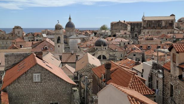 Blick über die Altstadt von Dubrovnik mit ihren charakteristischen roten Ziegeldächern und historischen Steingebäuden vor dem blauen Meer.