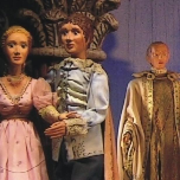 Drei Marionettenfiguren, möglicherweise aus einer Inszenierung der „Zauberflöte“, stehen nebeneinander.