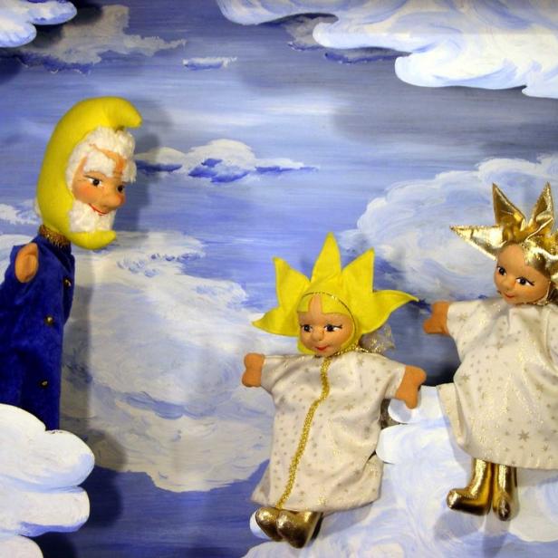 Puppenspiel mit Sonne, Mond und Sternchen vor einem gemalten Himmel.