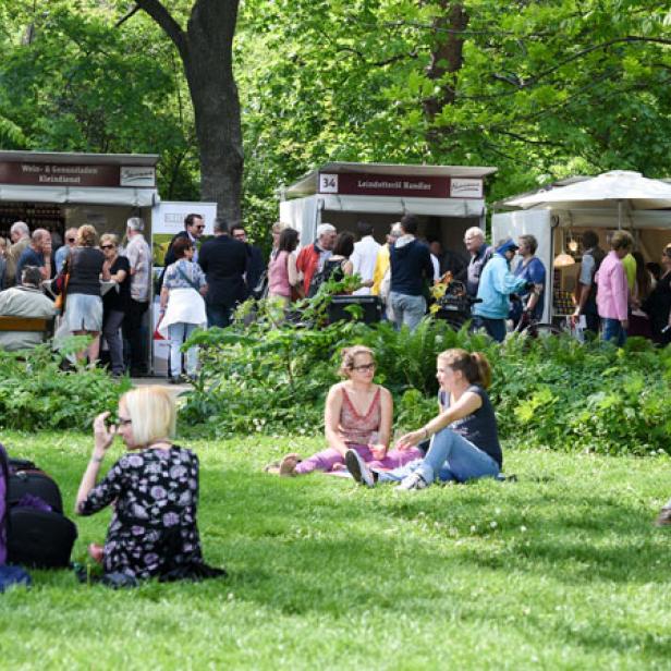 Menschen besuchen einen Markt im Freien an einem sonnigen Tag.