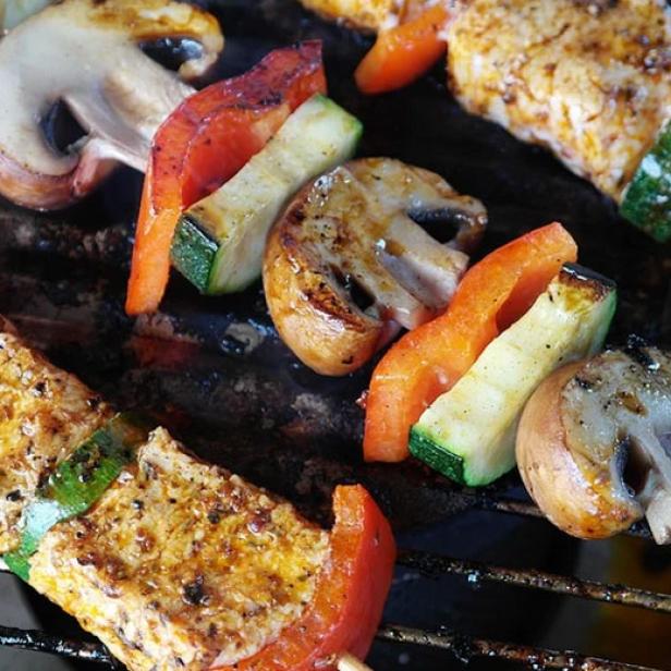 Gemüse- und Tofuspieße werden auf einem Grill zubereitet.