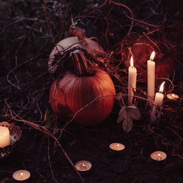 Kürbisse und brennende Kerzen in einer dunklen Halloween-Szene.
