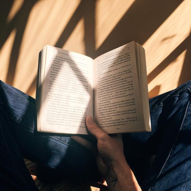 Eine Person liest ein Buch mit dem Titel „Harry Potter und der Feuerkelch“ im Kapitel 21.
