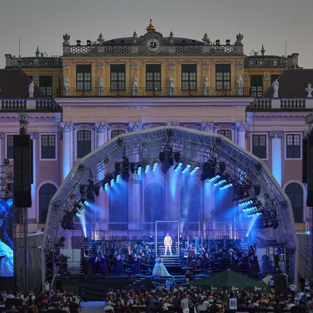 Eine Aufführung vor dem Schloss Schönbrunn mit Orchester und Sänger auf der Bühne.